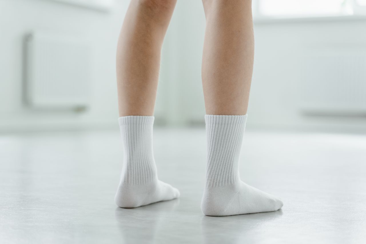services-01 Minimalist image focusing on legs in white socks standing indoors.